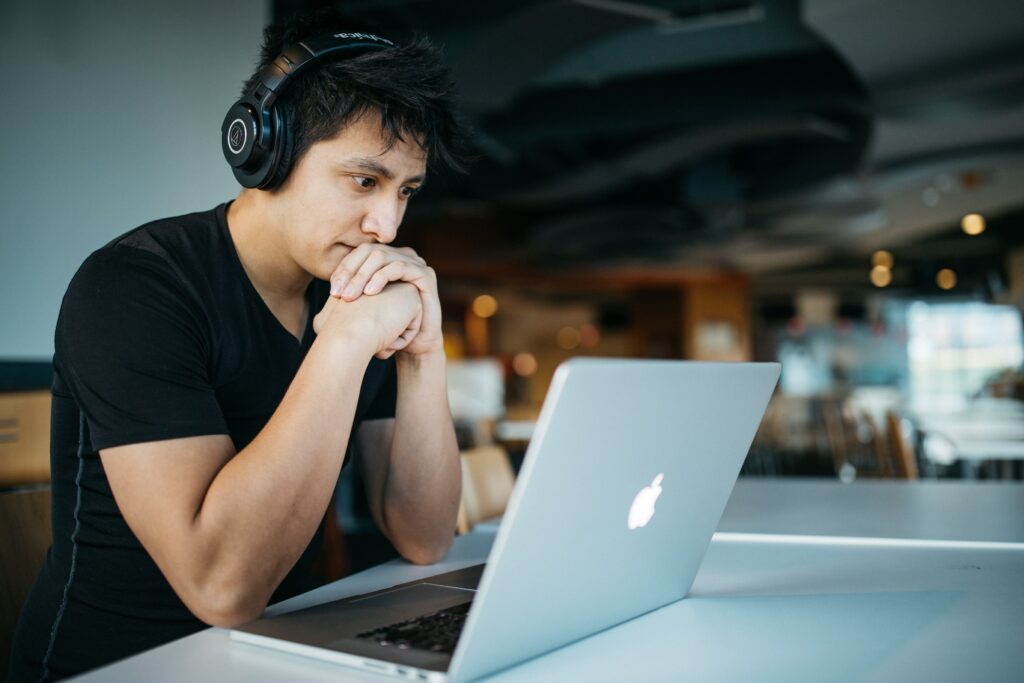 student with headphones watching video on a MacBook